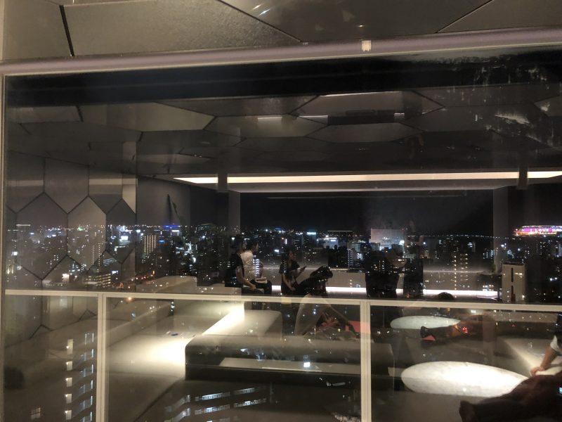 ホテルの最上階でガラスに写ったヨガをする生徒